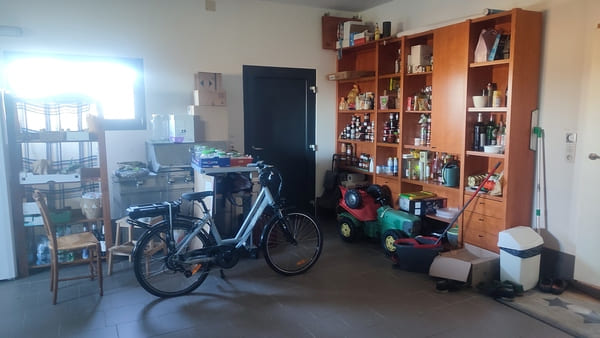 Grand garage avec étagères, vélo et espace de stockage dans la maison à vendre en Alsace