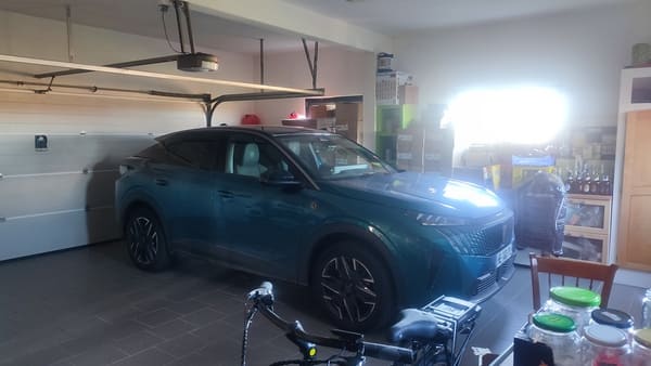 Garage intérieur carrelé avec voiture stationnée et accès direct à la maison à vendre à Saint-Bernard