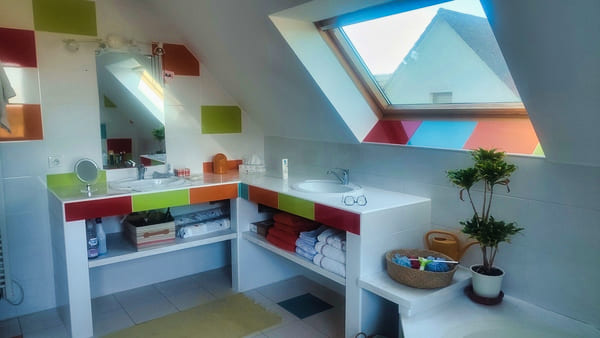 Salle de bain sous combles avec baignoire et lumière naturelle