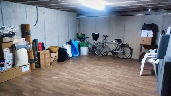 Grande pièce de sous-sol avec cartons vélos et rangements
